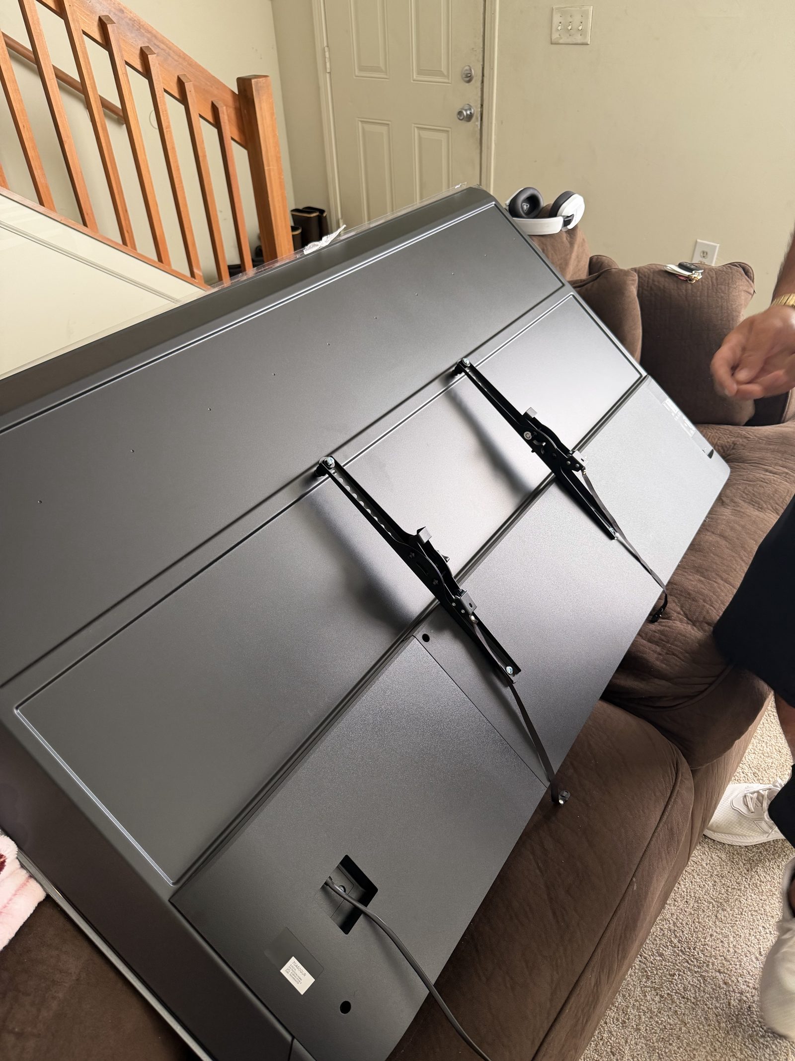 Full-motion TV wall mount bracket attached to the back of a large TV during installation