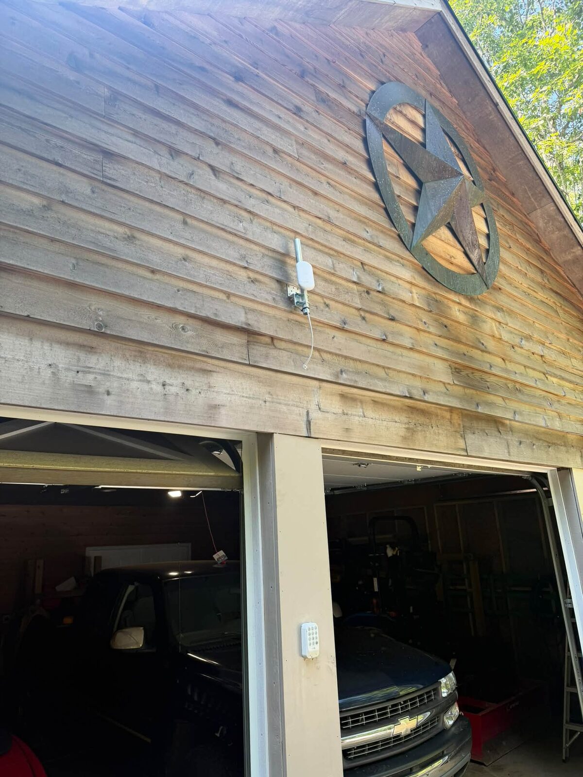 Wireless bridge antenna on a pole bracket beside a wood-sided garage extending network coverage