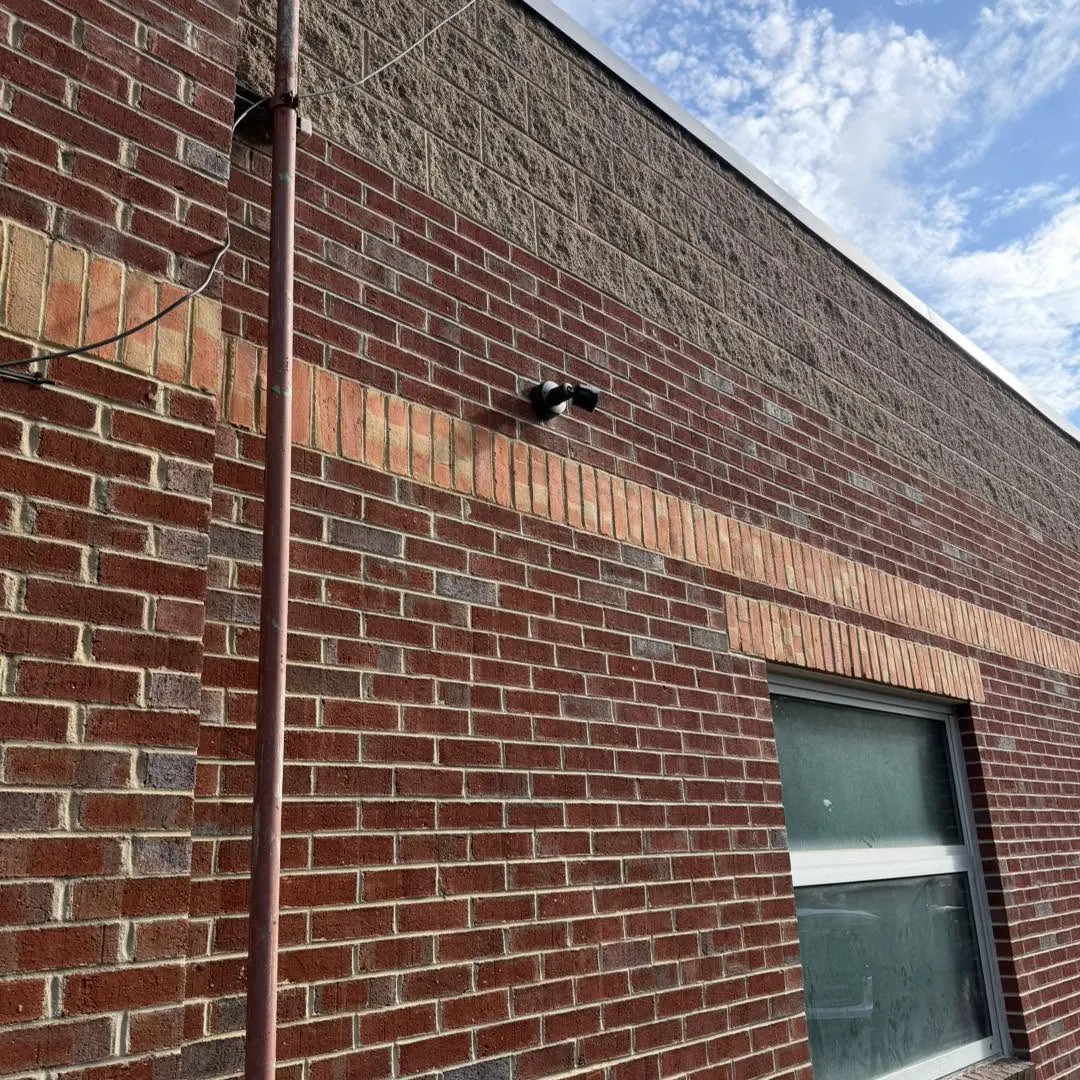 Close-up of a business security camera mounted on a brick wall at Rally House