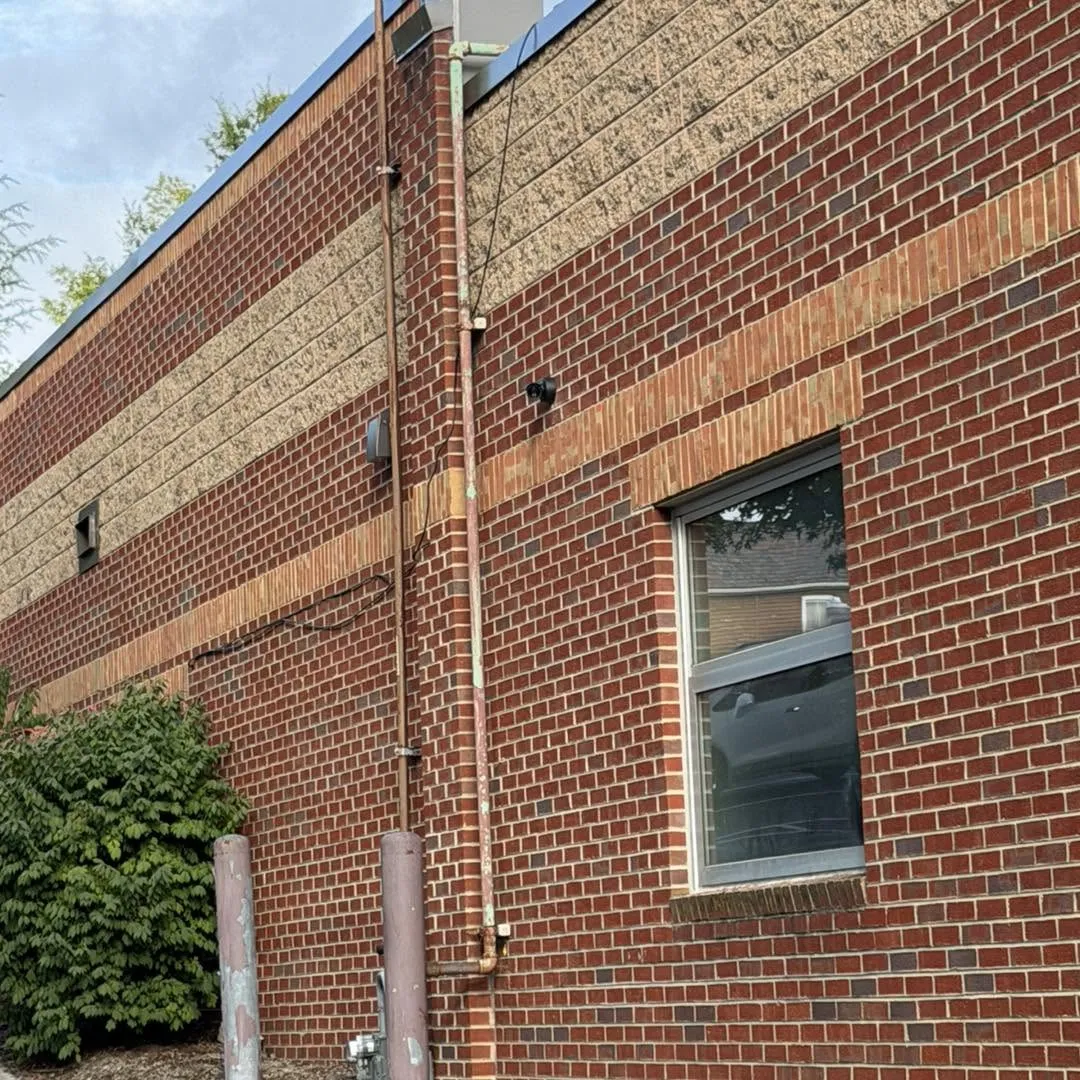 Commercial surveillance camera mounted on a brick retail building exterior near a window