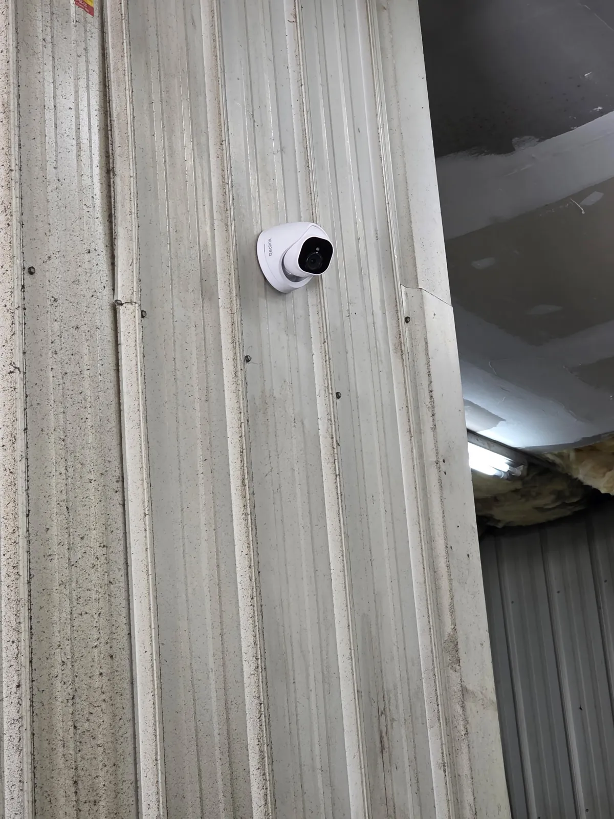 Close-up of a wired Reolink dome security camera mounted on a metal wall at Redline Tire and Lube