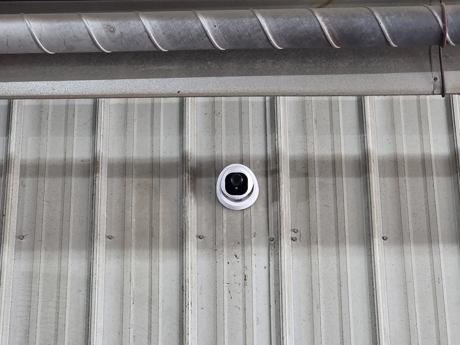 Wired dome security camera mounted on a corrugated metal shop wall in Christiansburg VA