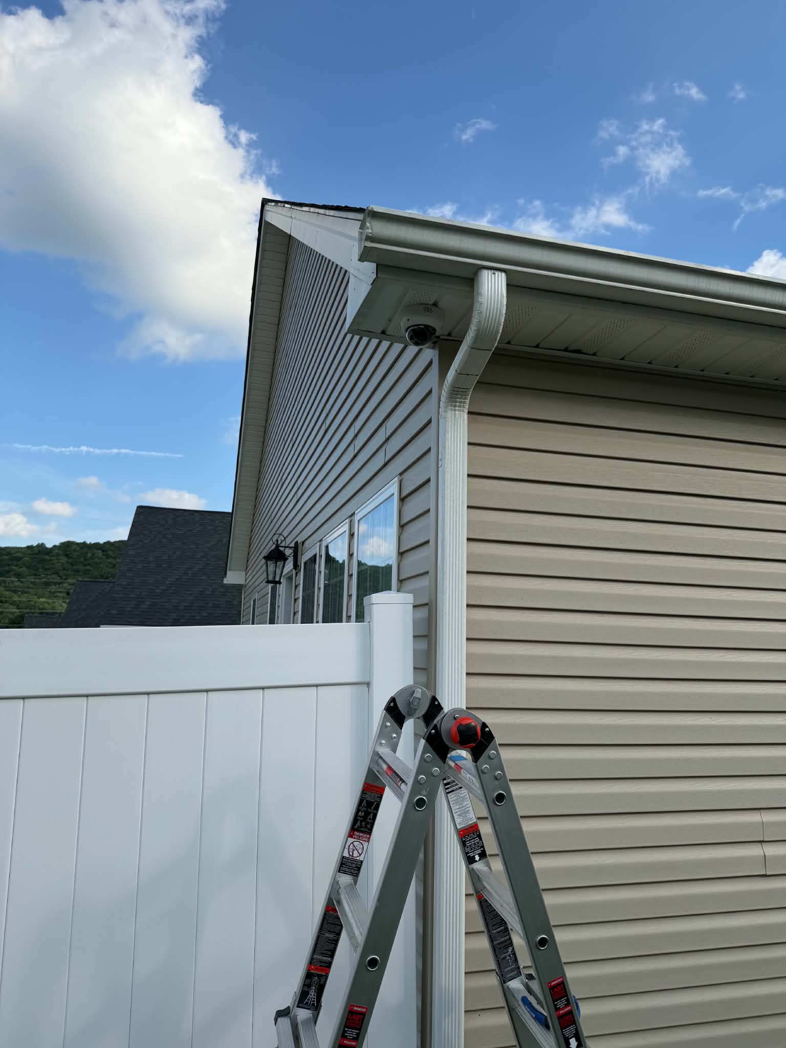 Technician running low-voltage cabling on a ladder for a camera pre-wire