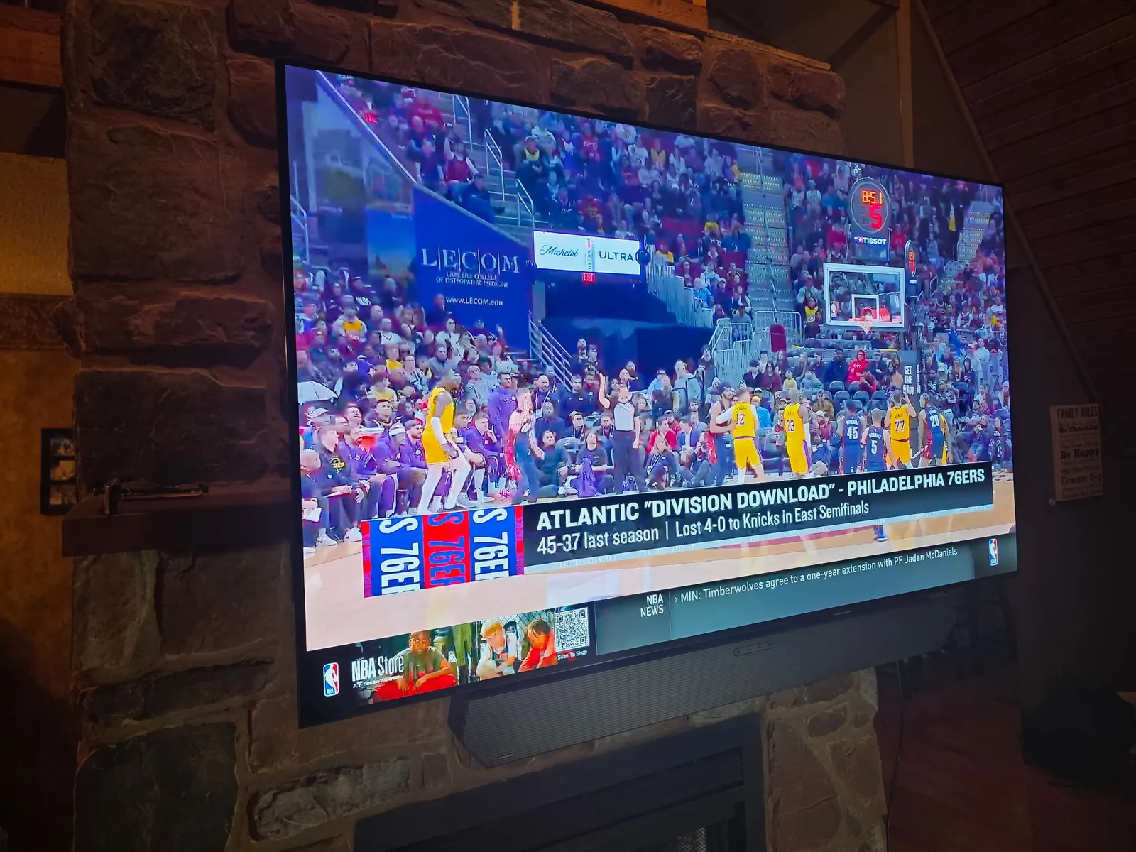 Side-angle close-up of a large television mounted on an irregular natural stone fireplace surface