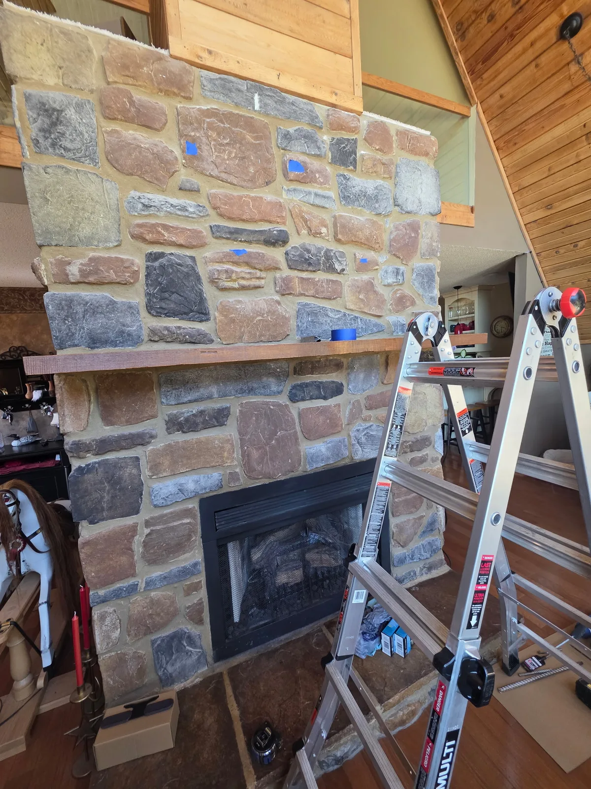 Stone fireplace before TV mounting, with painter's tape marking the planned TV mount layout