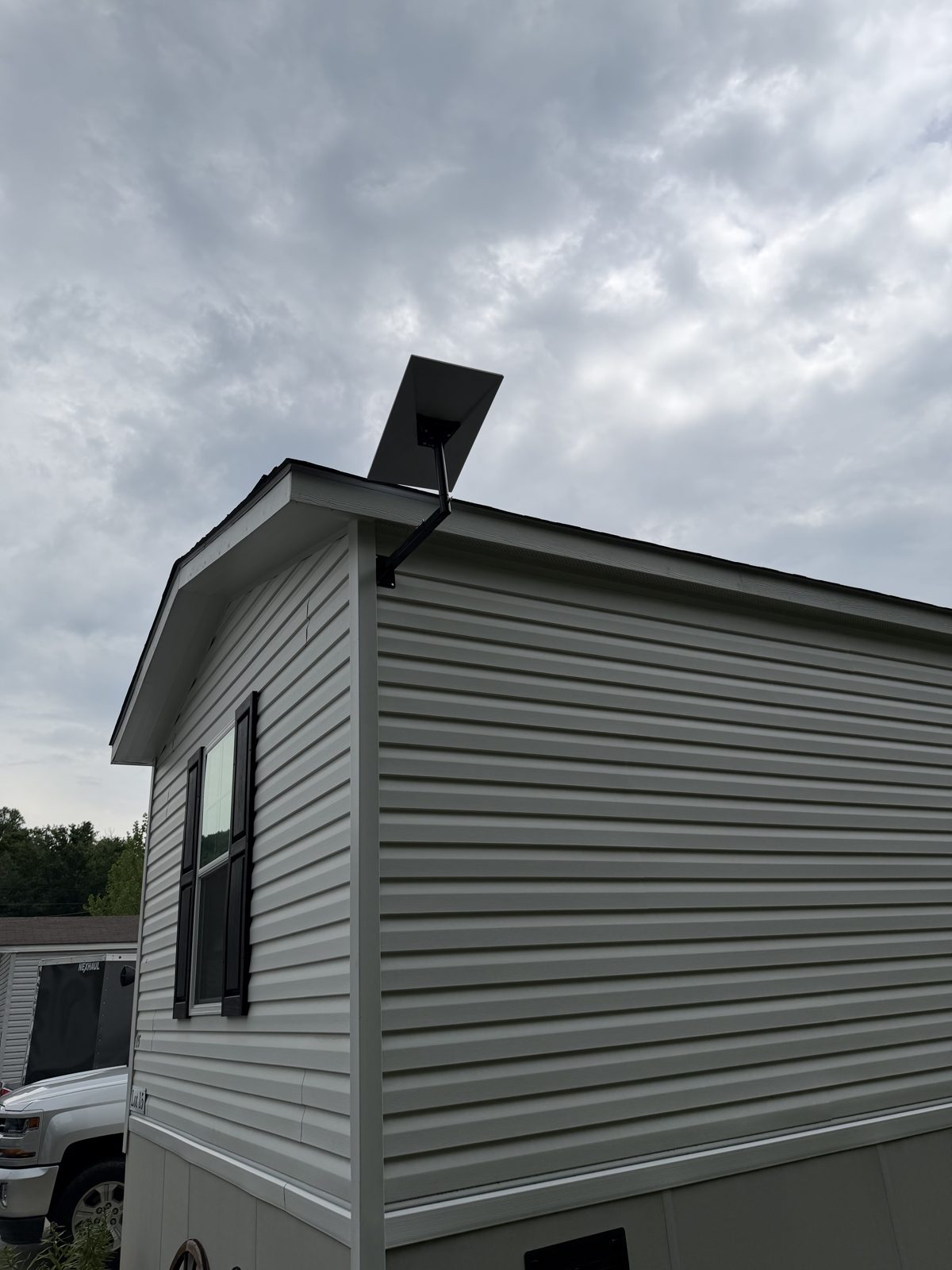 Starlink dish on a roof-edge pole mount above white siding