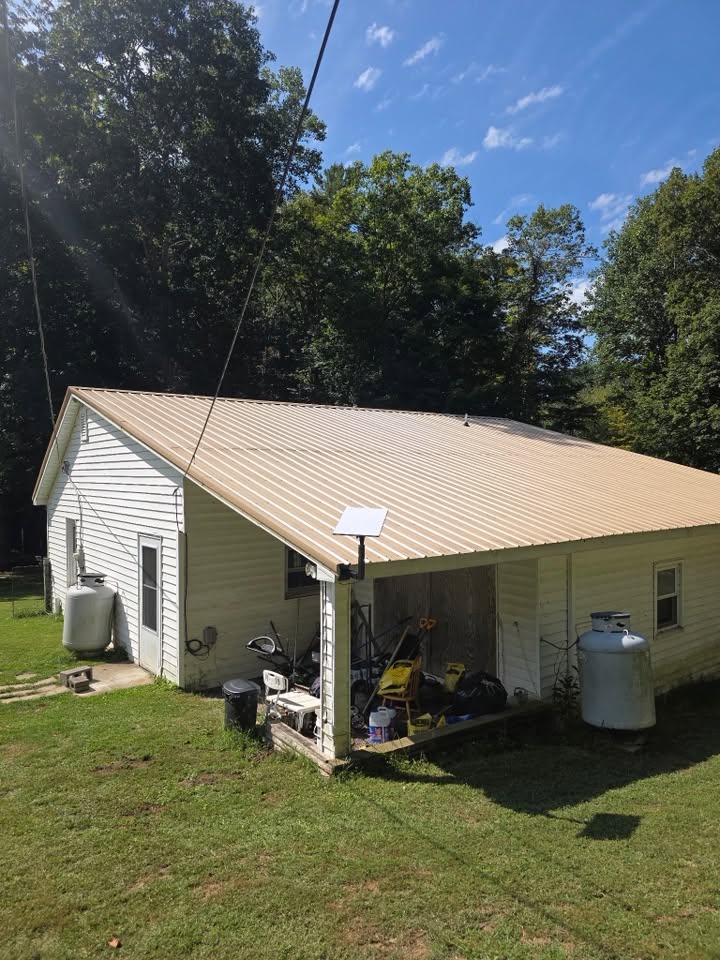 Starlink dish on a pole mount beside a metal-roof outbuilding on a rural Virginia property