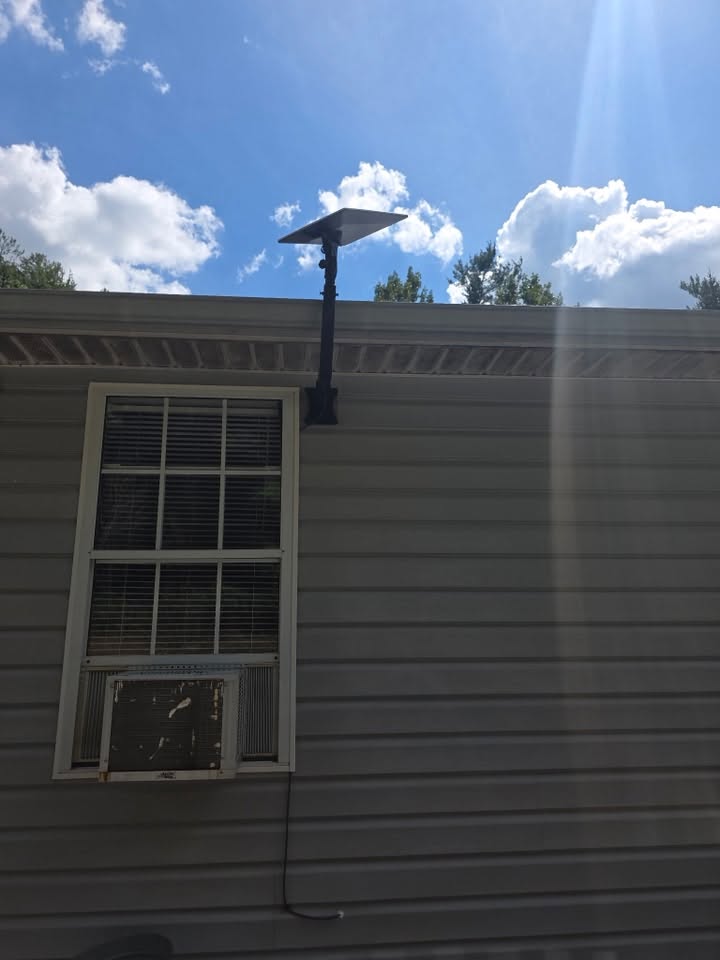 Starlink dish mounted on a black J-pole at the roofline of a Southwest Virginia home